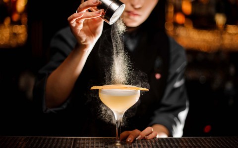 bartender pouring cinnamon to a cocktail cup