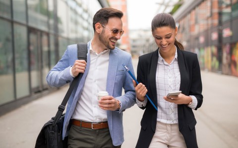 a woman and a man walking and looking at a cellphone 