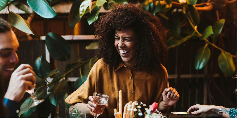woman laughing and holding cocktail