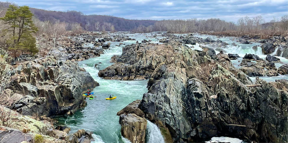 large river surrounded by rock with several kayaks floating