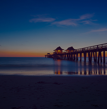 view from beach overlooking ocean and pier at sunset