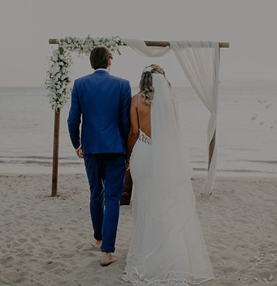 couple walking to wedding alter situated along the beach shoreline