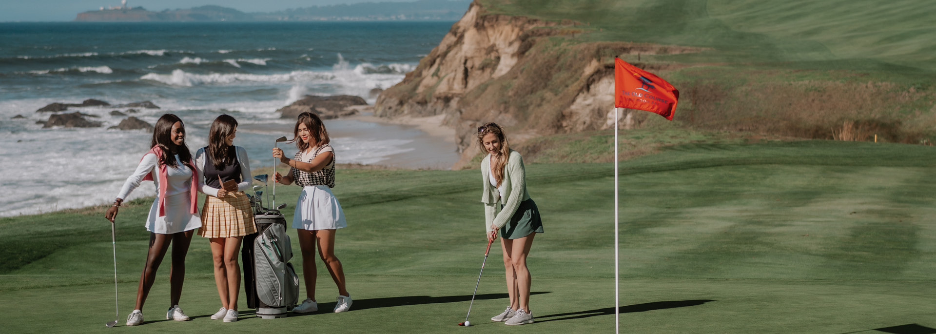 group of ladies putting at a golf course by the ocean