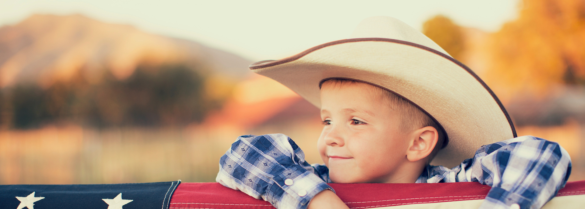 child wearing cowboy hat and turned to the side smiling