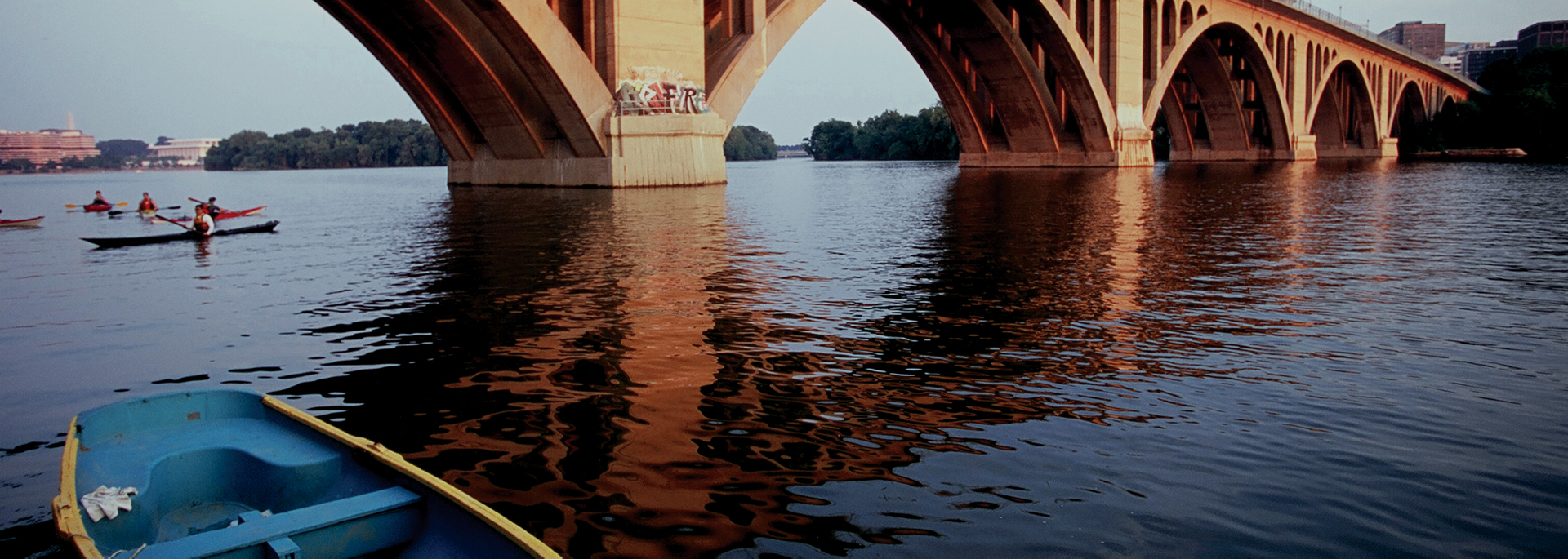 front of blue kayak floating on rive under large bridge