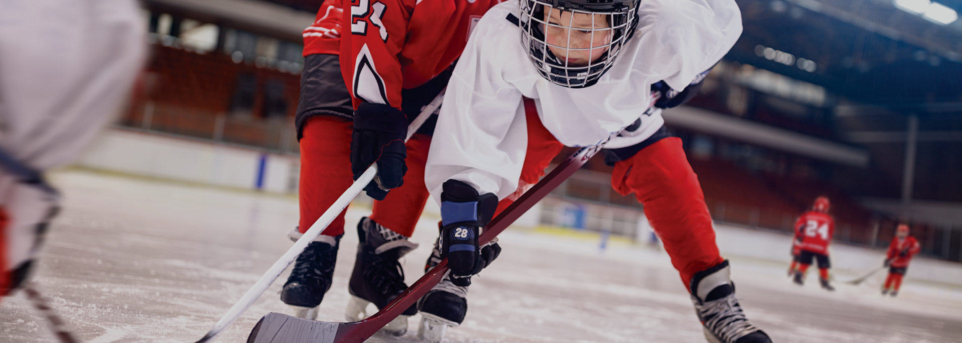 child in white jersey and hockey gear holding stick 