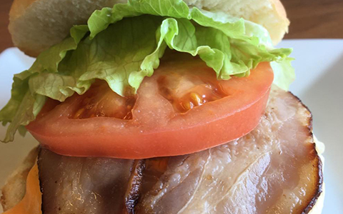 Hamburger topped with lettuce, tomato, and bacon