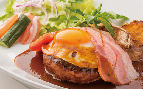 A hamburger steak topped with egg and bacon and a side salad