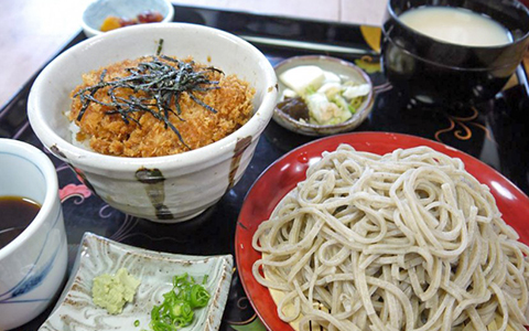 A plate of cold soba noodles and a rice bowl with fried chicken