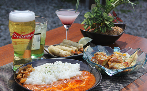 A plate of curry rice, fried chicken, shrimp egg rolls and beverages
