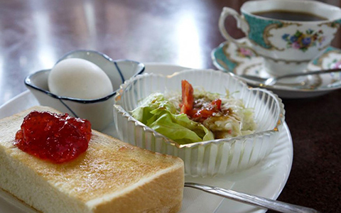 A breakfast set meal of toast, salad, boiled egg with a cup of coffee