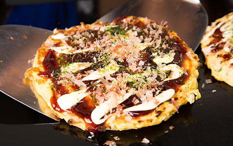 Okonomiyaki being picked off the hot plate