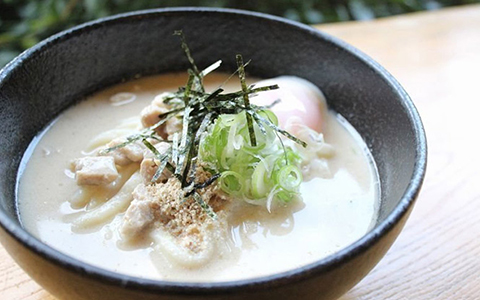 Hot udon in a creamy white broth topped with seaweed and spring onions