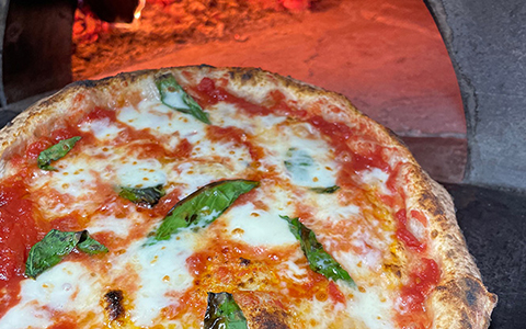 Freshly cooked pizza being taken out of the pizza oven