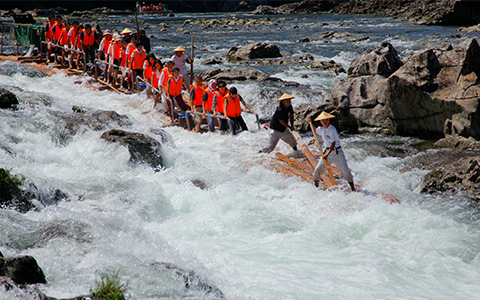 Tourists riding a log raft on a river