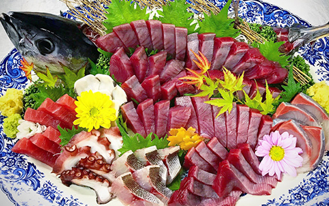 A big plate filled with sashimi and a head of a fish for decoration