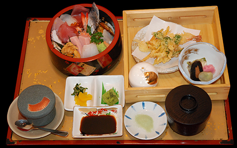 A tray with a sashimi bowl, tempura, rice, and miso soup