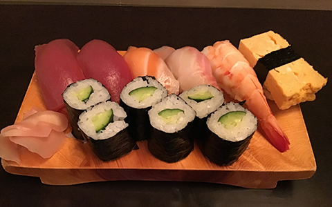 A plate of tuna, salmon, shrimp, egg sushi with cucumber rolls