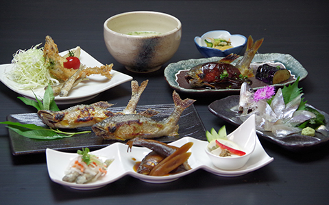 Dishes of grilled fish, boiled vegetables, sashimi with soup