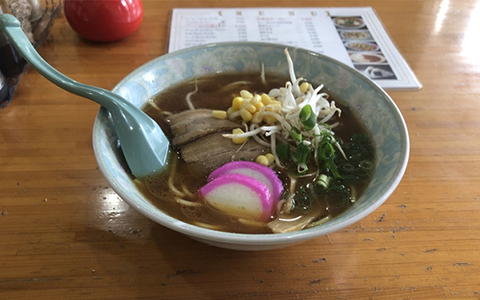 A bowl of ramen with corn, sliced pork, and bean sprouts