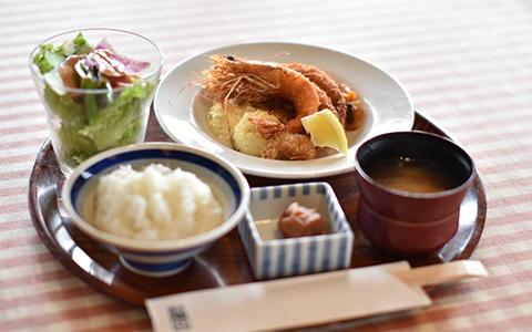 A dish of large shrimp and rice, miso soup, and salad