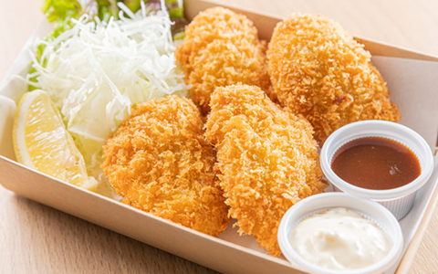 A box filled with fried oysters, cabbage, and sauce in small containers