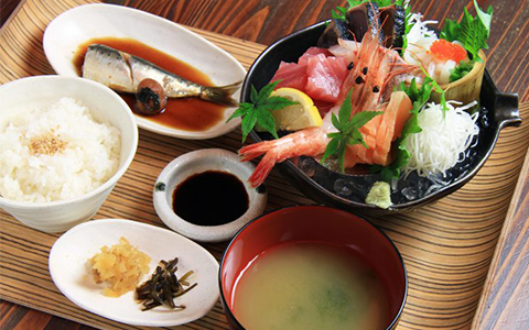 A bowl of sashimi and rice, miso soup, and boiled fish