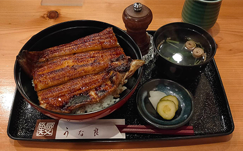 Grilled eel on top of rice with soup and pickles on the side