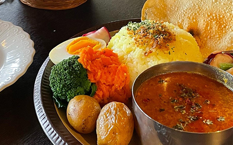 A silver platter with curry, rice, vegetables and naan