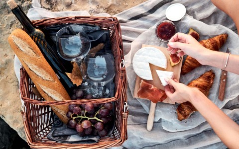 a picnic with a basket filled with croissants, cheese and wine