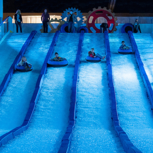 children sitting in inner tubes and riding down a slide made of ice