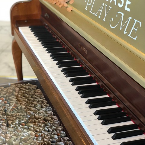 A wood piano with a writing on it that says pease play me. 