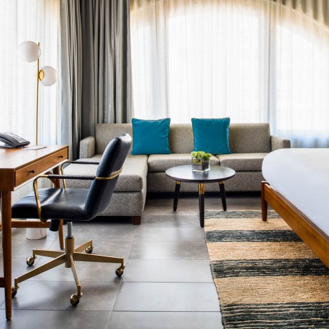 a room with a large bed , a desk, a couch and a window
