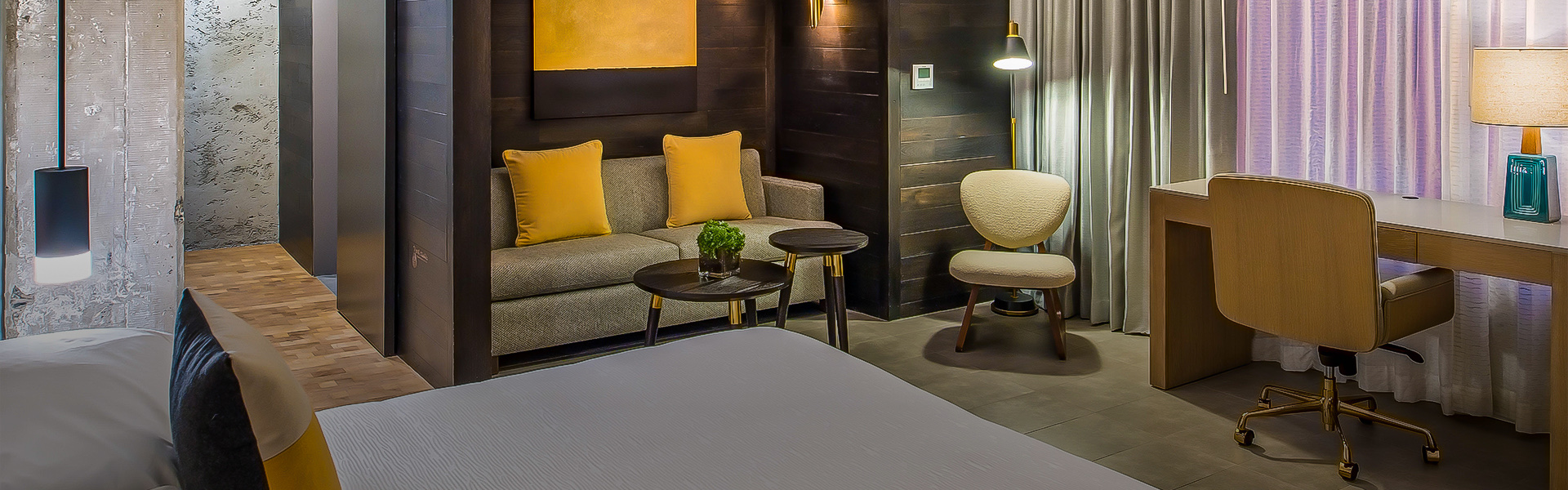 A room with a bed, a couch, an armchair and a desk.