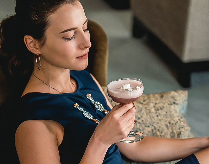 A woman holding a cocktail on a couch