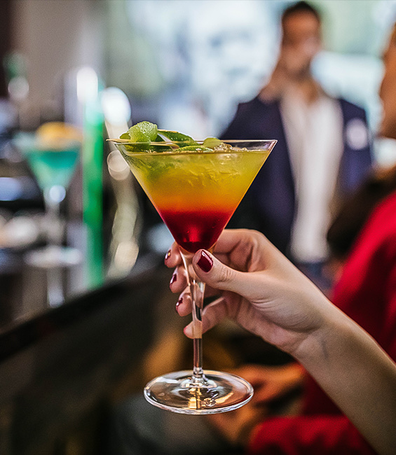 A woman holding a cocktail on the bar.
