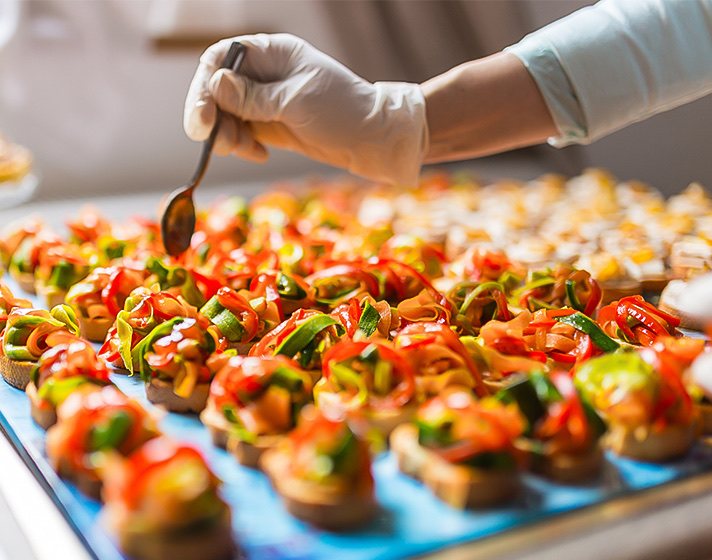 A chef putting on some dip on a plate with appetizers