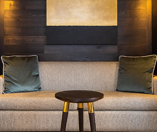 A couch with two cushions and a wood table in the middle of it
