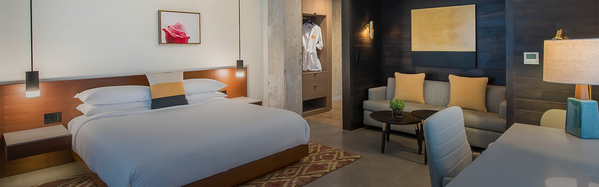 A room with a large bed, a closet, a couch and a desk