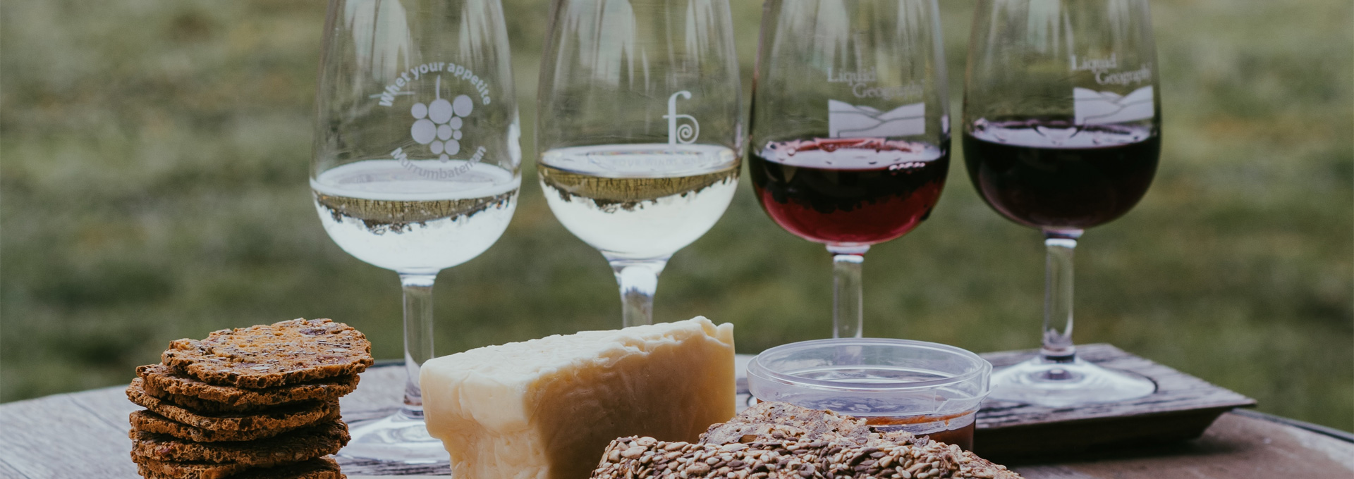 four wine glasses on a table with cheese and bread