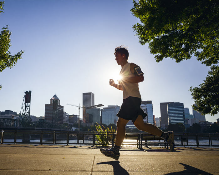 man running outside with the city behind him