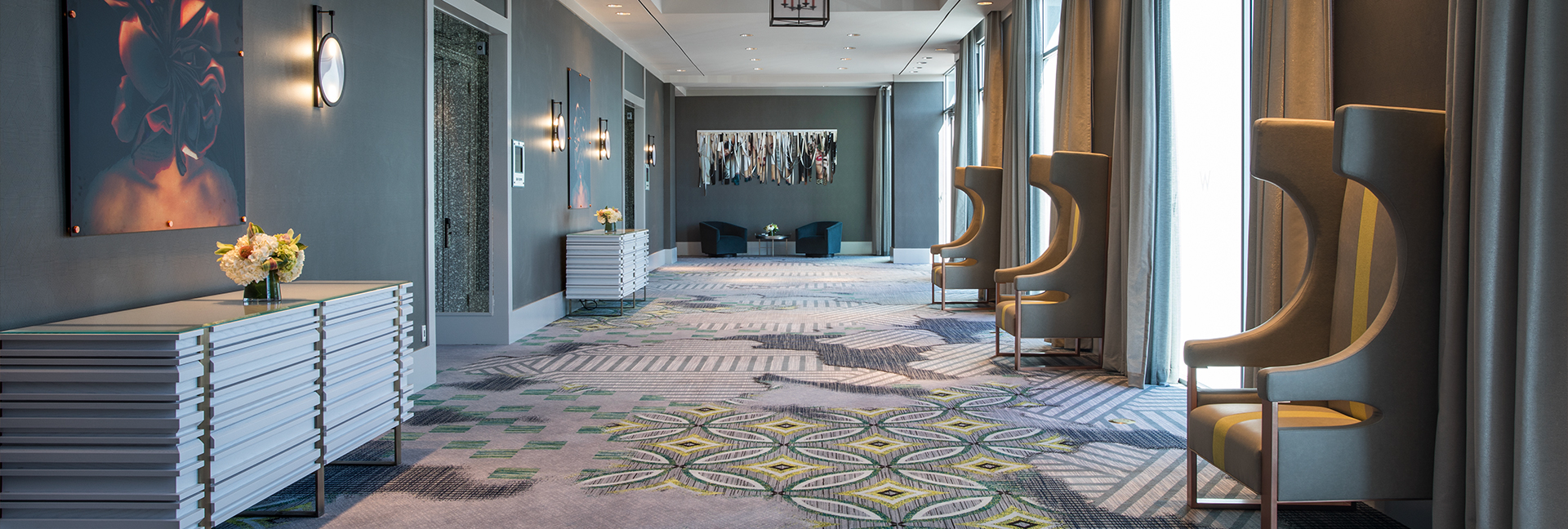 Wide hotel corridor with gray colors and accent carpet floor