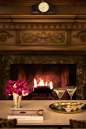 two cocktails by the fire with snacks