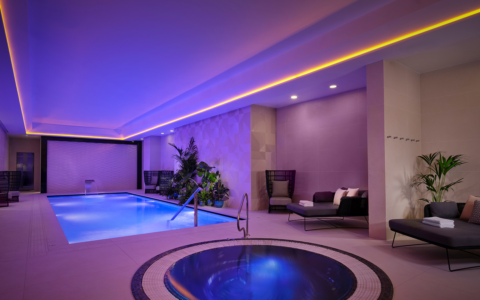 indoor circular hot tub next to pool and lounge chairs