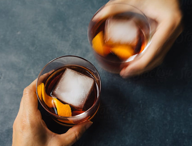hands holding two whiskey on the rocks