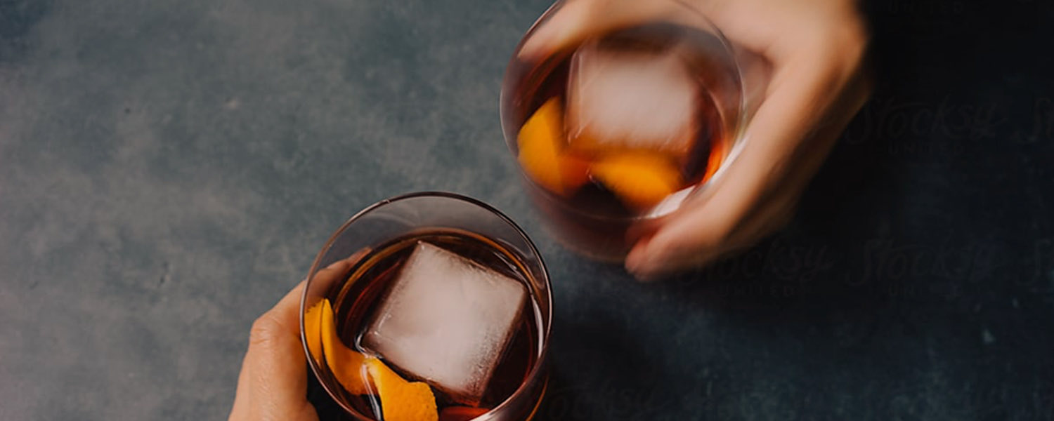 two whiskeys with large ice in motion