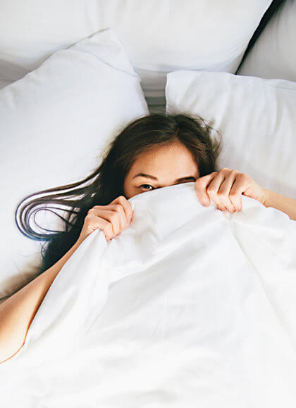 woman in bed covering her face