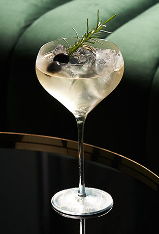 a cocktail garnished with olives and a piece of rosemary