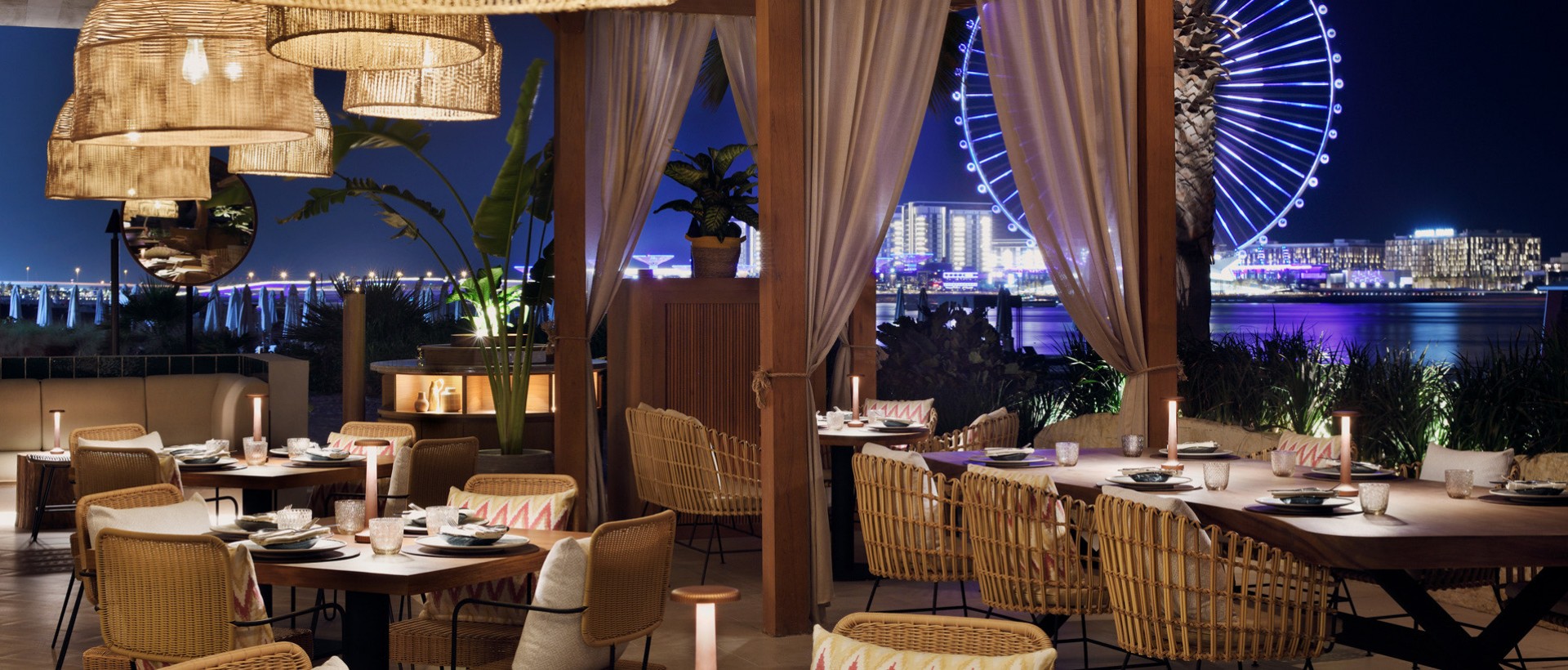 dining at night with ferris wheel and the city lit up in the back