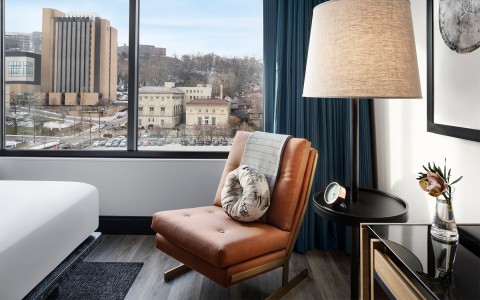 a light brown chair in a low lit room with a view of the city just outside of the window